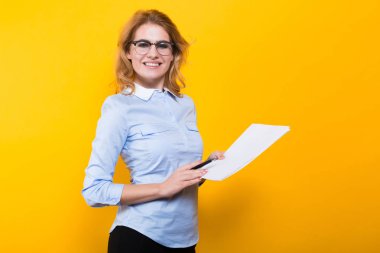 Belgeler ve kalem tutan ve kameraya bakarak genç sarışın iş kadını