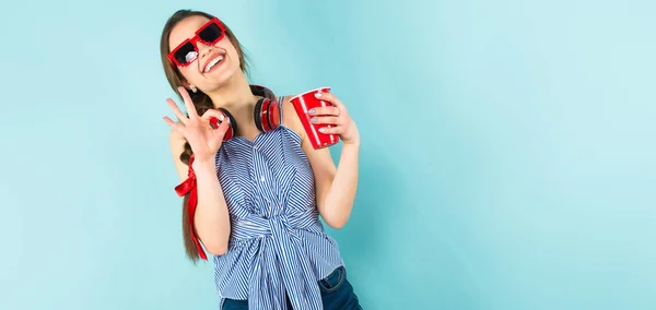 Pretty Brunette Girl Modern Headpones Holding Plastic Cup Showing Gesture — Stock Photo, Image
