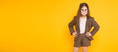 Ciddi sevimli küçük kız kameraya poz sarı arka planı süre seyir 