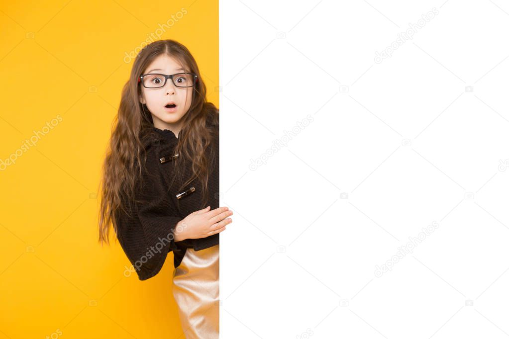 Surprised cupe little  girl with blank billboard on yellow background