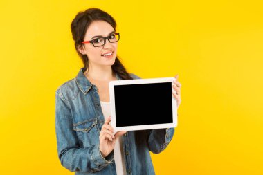 Genç esmer kadın gösteren dijital tablet ile boş perde