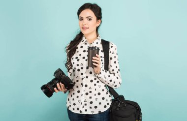 Dijital fotoğraf makinesi ve kağıt bardak kahve tutan genç esmer kadın