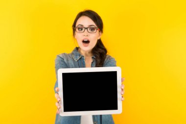 Sürpriz genç esmer kadın gösteren dijital tablet ile boş perde