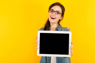 Genç esmer kadın gösteren dijital tablet ile boş perde