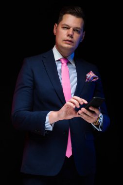 Yakışıklı delikanlı Smartphone karanlık studio arka plan kullanarak 