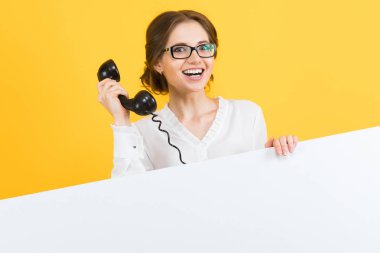Retro telefon tutarak ve kameraya gülümseyen genç esmer kadın