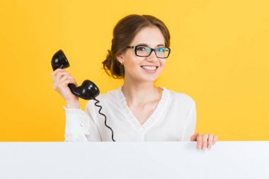 Retro telefon tutarak ve kameraya gülümseyen genç esmer kadın
