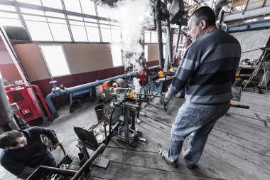 Sıcak cam ile çalışma işlemi sırasında cam fabrikasında çalışan insanlar