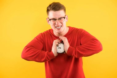 Çalar saat her iki elinde tutan kızgın sarışın adam