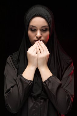 Geleneksel giysiler içinde kapalı gözlerle dua eden genç Müslüman kadın portresi