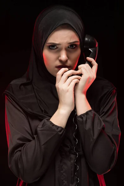 portrait of young Muslim woman holding handset of vintage phone