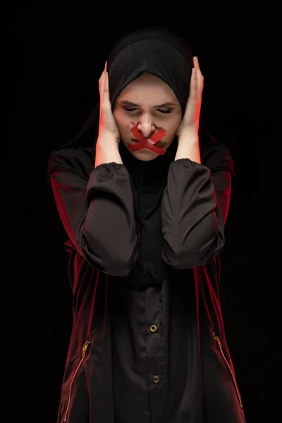 手で耳を閉じて口の中に赤い十字架の若いイスラム教徒の女性 — ストック写真