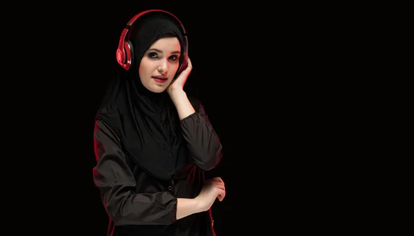 黒地にピンクのイヤホンの若いイスラム教徒の女性の肖像画 — ストック写真