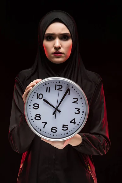 portrait of young Muslim woman holding vintage clock