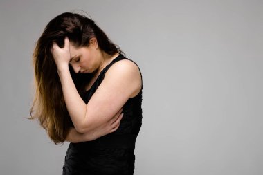 Studio gri duvar farklı ifadeler gösterilen basit siyah gömlekli uzun lüks saçlı güzel curvy esmer kadın. Kafa tutan.