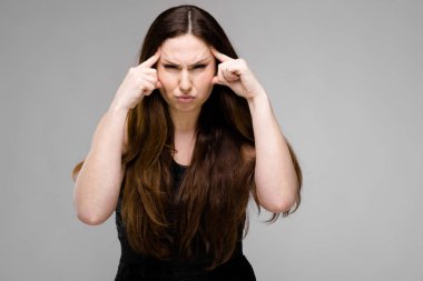 Studio gri duvar farklı ifadeler gösterilen basit siyah gömlekli uzun lüks saçlı güzel curvy esmer kadın. 