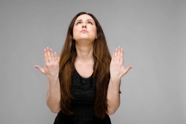 Studio gri duvar farklı ifadeler gösterilen basit siyah gömlekli uzun lüks saçlı güzel curvy esmer kadın.