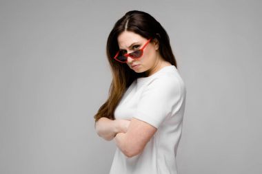 Studio gri duvar farklı ifadeler gösterilen basit beyaz t-shirt uzun lüks saçlı güzel curvy esmer kadın.