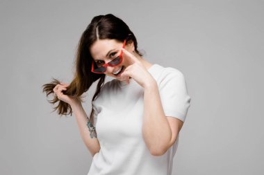 Studio gri duvar farklı ifadeler gösterilen basit beyaz t-shirt uzun lüks saçlı güzel curvy esmer kadın.