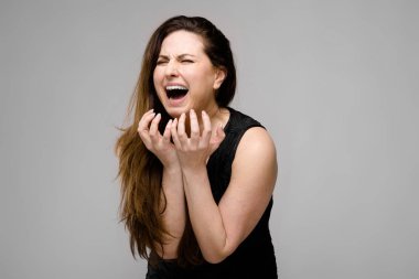 Studio gri duvar farklı duygusal ifadeler gösterilen basit siyah gömlekli uzun lüks saçlı güzel curvy esmer kadın.