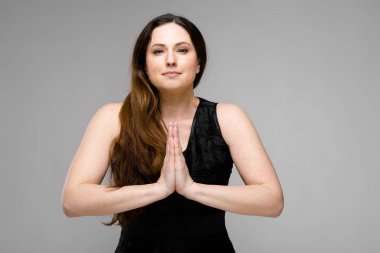 Studio gri duvar farklı ifadeler gösterilen basit siyah gömlekli uzun lüks saçlı güzel curvy esmer kadın.