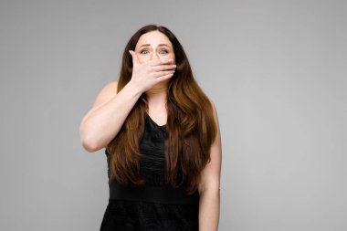 Studio gri duvar farklı ifadeler gösterilen basit siyah gömlekli uzun lüks saçlı güzel curvy esmer kadın.