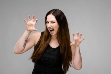 Studio gri duvar farklı ifadeler gösterilen basit siyah gömlekli uzun lüks saçlı güzel curvy esmer kadın.