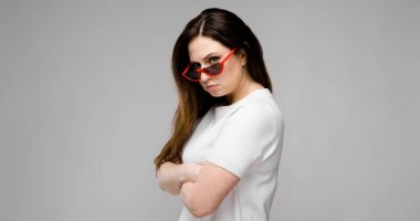 Studio gri duvar farklı ifadeler gösterilen basit beyaz t-shirt uzun lüks saçlı güzel curvy esmer kadın.