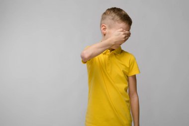 Sevimli sarışın beyaz varoluş çocuk parlak t-shirt beyaz duvar Studio farklı ifadeler gösteriliyor. Gözleri el ile gizleme.