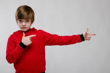 Gündelik kıyafeti Studio beyaz duvar üzerinde farklı ifadeler gösterilen iyi preteen beyaz çocuk. İki elinle sağa işaret eden.