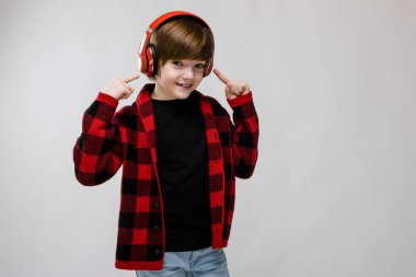 İyi preteen beyaz çocuk kırmızı kulaklık müzik dinlemek ve beyaz duvar Studio farklı ifadeler gösterilen gündelik kıyafeti.