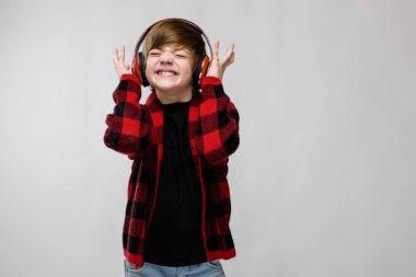 İyi preteen beyaz çocuk kırmızı kulaklık müzik dinlemek ve beyaz duvar Studio farklı ifadeler gösterilen gündelik kıyafeti.