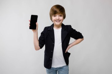 İyi preteen beyaz çocuk farklı ifadeler gösterilen ve beyaz duvar Studio smartphone tutan gündelik kıyafeti.