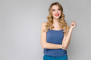 Çekici genç Beyaz sarışın kadın rahat kıyafet Studio gri duvar farklı ifadeler gösterilen. 