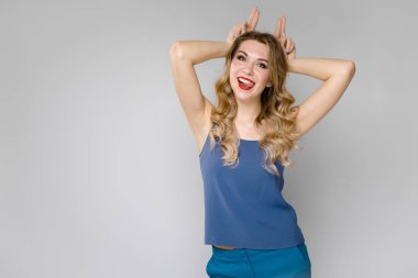 Çekici genç Beyaz sarışın kadın rahat kıyafet Studio gri duvar farklı ifadeler gösterilen. 