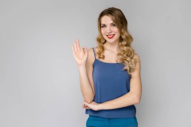 Çekici genç Beyaz sarışın kadın rahat kıyafet Studio gri duvar farklı ifadeler gösterilen. 