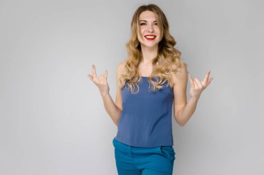 Çekici genç Beyaz sarışın kadın rahat kıyafet Studio gri duvar farklı ifadeler gösterilen. 