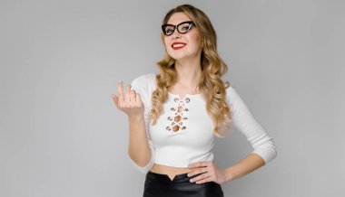 Çekici genç Beyaz sarışın kadın rahat kıyafet ve beyaz duvar Studio farklı ifadeler gösteren gözlük. 