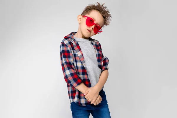 カジュアルな服装と白い壁のスタジオでの異なる表現を示す赤いサングラスの素敵な白人幼児少年 — ストック写真