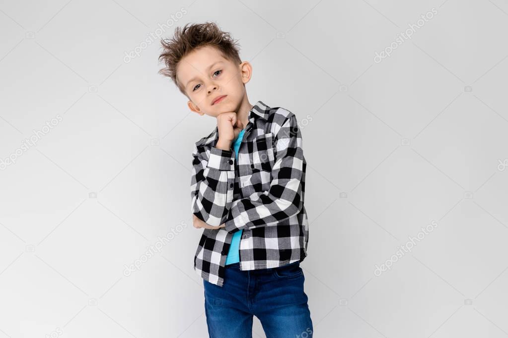 Nice caucasian preschooler boy in casual outfit showing different expressions on white wall in studio. 