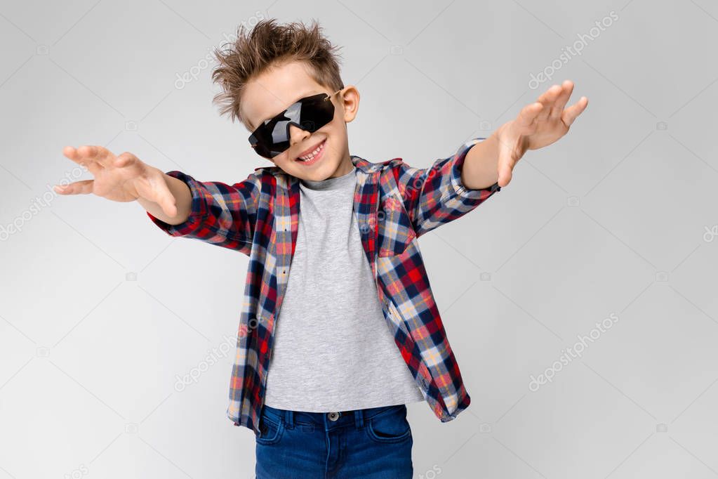 Nice caucasian preschooler boy in casual outfit and sunglasses showing different expressions on white wall in studio.