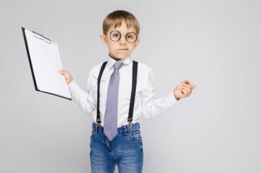 Çok güzel ciddi emin küçük çocuk Pano gri arka plan üzerinde tutarak bardaklarda portresi