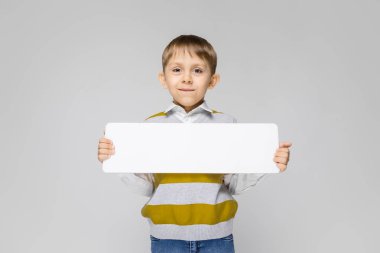 Boş levha gri arka plan üzerinde tutarak sevimli küçük çocuk portresi
