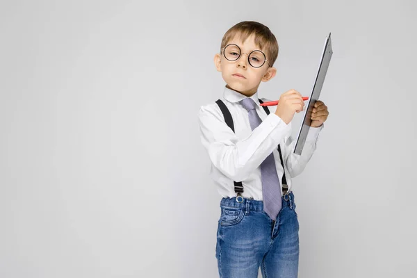 肖像可爱的认真自信的小男孩在眼镜持有剪贴板灰色背景 — 图库照片