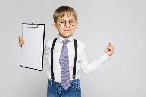 Retrato Adorável Sério Confiante Menino Óculos Segurando Prancheta Fundo Cinza — Fotografia de Stock