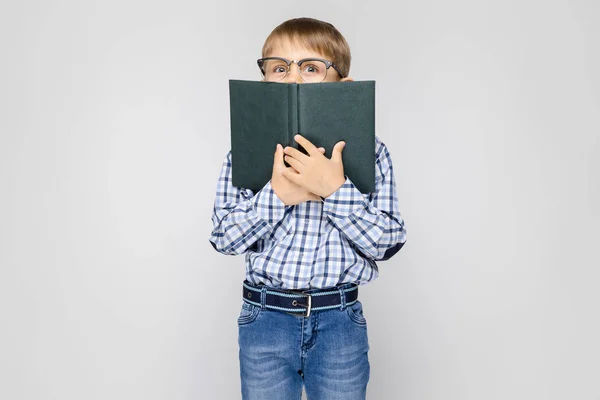 Portret Ładny Mały Chłopiec Okularach Prowadzące Księgę Szarym Tle — Zdjęcie stockowe