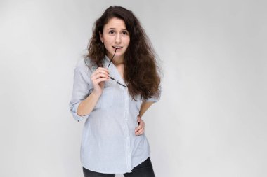 Gri izole gözlük tutan çekici genç kıvırcık esmer beyaz kadın