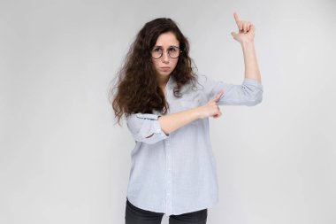 Gri izole çekici genç kıvırcık esmer beyaz kadın işaret gözlük