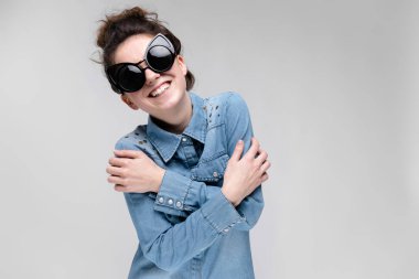 Gri izole güneş gözlüğü takıyor topuz saç modeli ile mutlu esmer beyaz kız