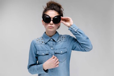 Gri izole güneş gözlüğü takıyor topuz saç modeli ile mutlu esmer beyaz kız